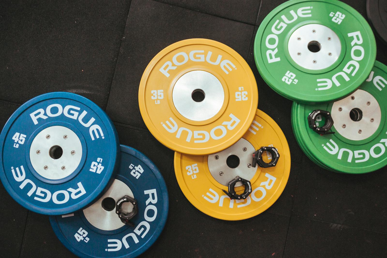 Colorful Rogue weight plates arranged on a gym floor visualizing fitness and strength.