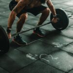 A muscular man in a gym preparing to lift a heavy barbell, showcasing strength and fitness.