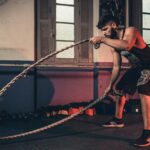 Man performing a challenging Crossfit rope exercise in an indoor gym setting.