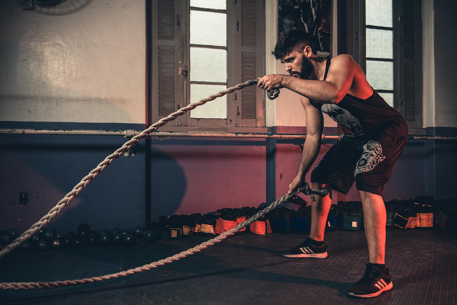 Man performing a challenging Crossfit rope exercise in an indoor gym setting.