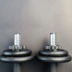 Close-up of two iron dumbbells on a gray background, perfect for strength training images.