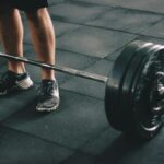 Close-up of a man deadlifting a heavy barbell in an indoor gym setting.