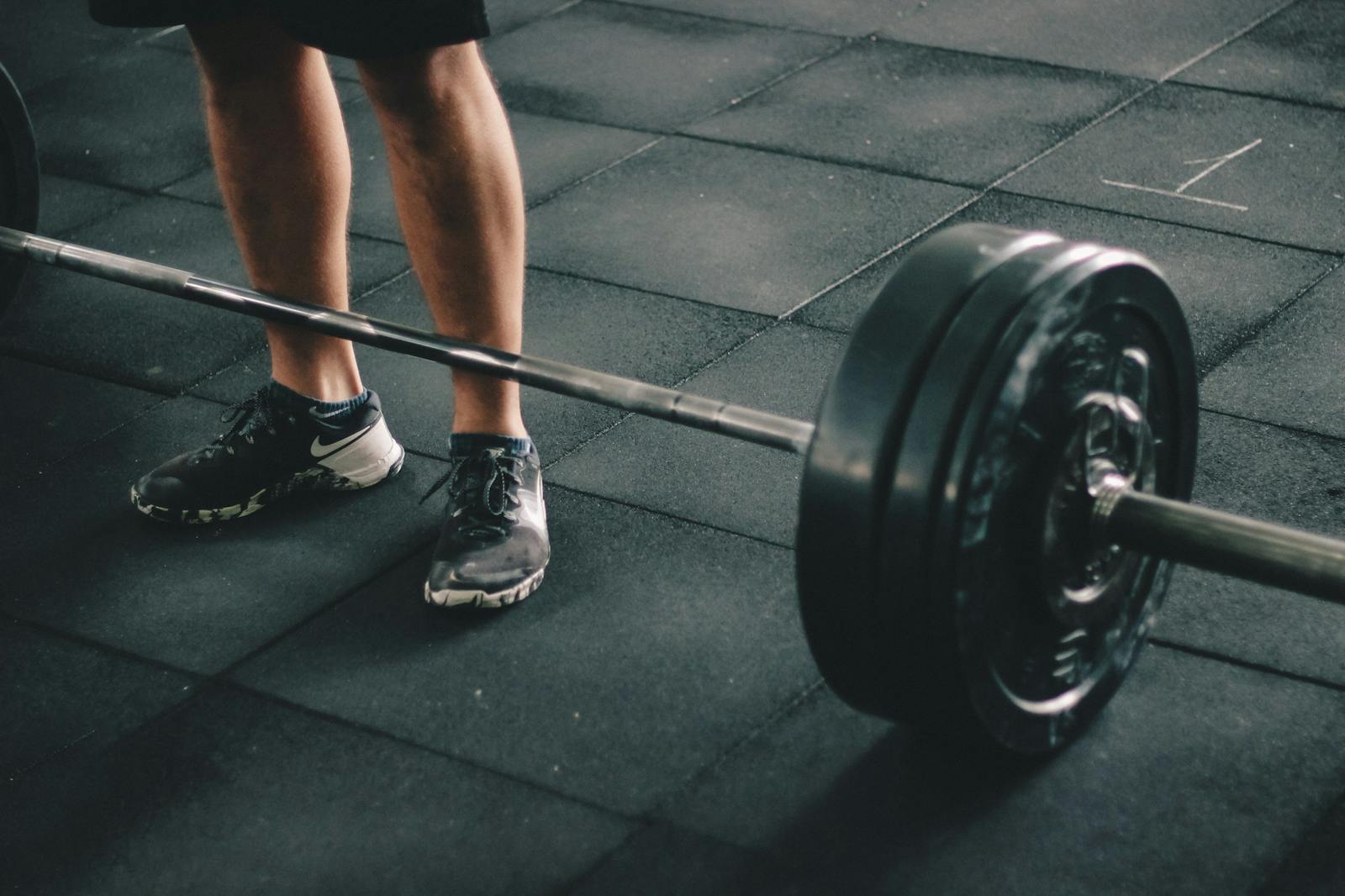 Close-up of a man deadlifting a heavy barbell in an indoor gym setting.