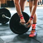 Athlete tightening barbell plates in a gym, emphasizing fitness and strength.