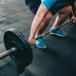 A man deadlifting a barbell indoors showcasing power, fitness, and dedication.