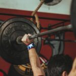 Athlete lifting heavy barbell during strength training session in gym.