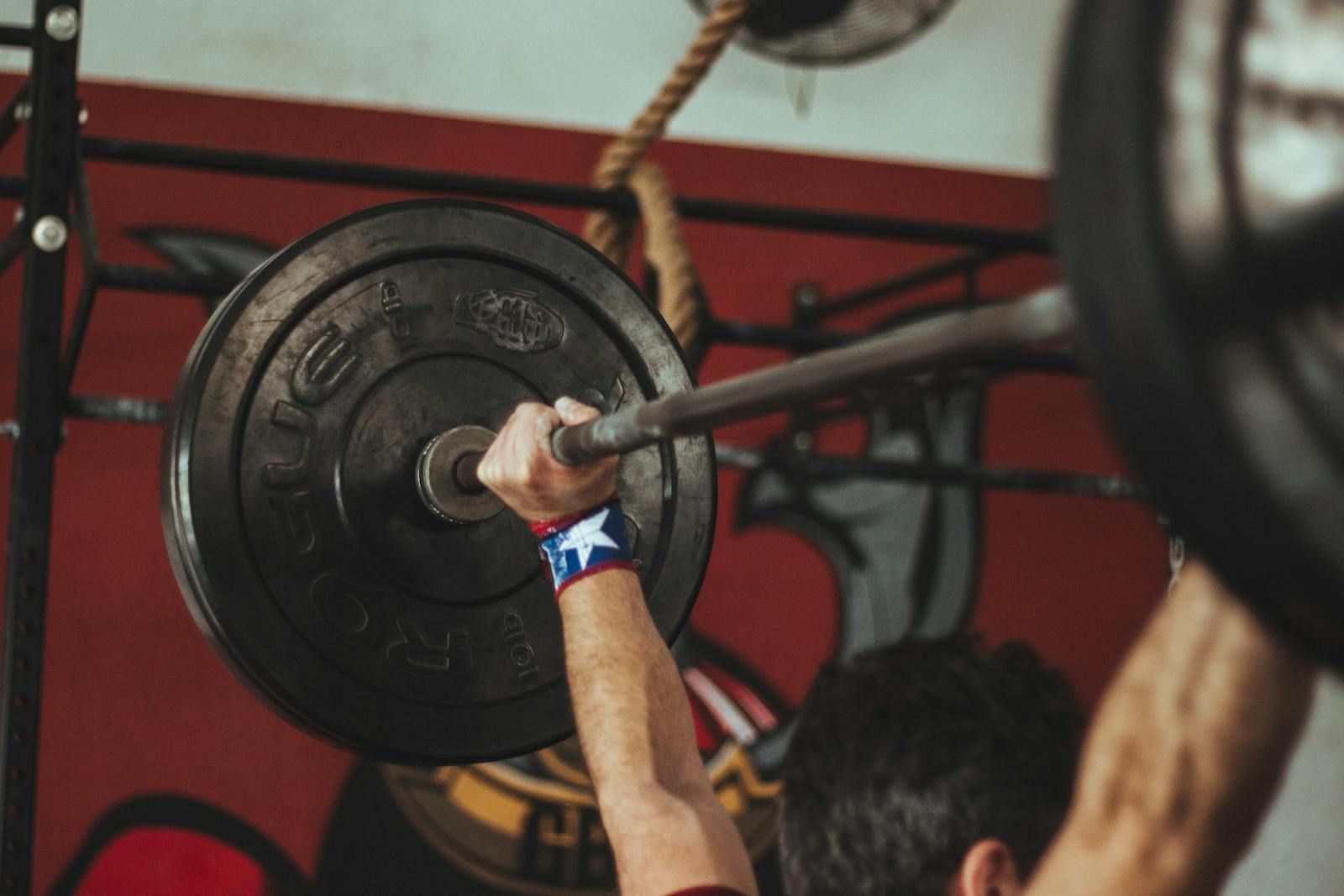 Athlete lifting heavy barbell during strength training session in gym.