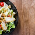 meat with vegetables and sliced tomatoes in black bowl