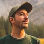 man in green crew neck shirt and black hat