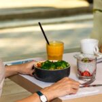 person holding black ceramic bowl with vegetable salad