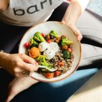 a woman is holding a bowl of food