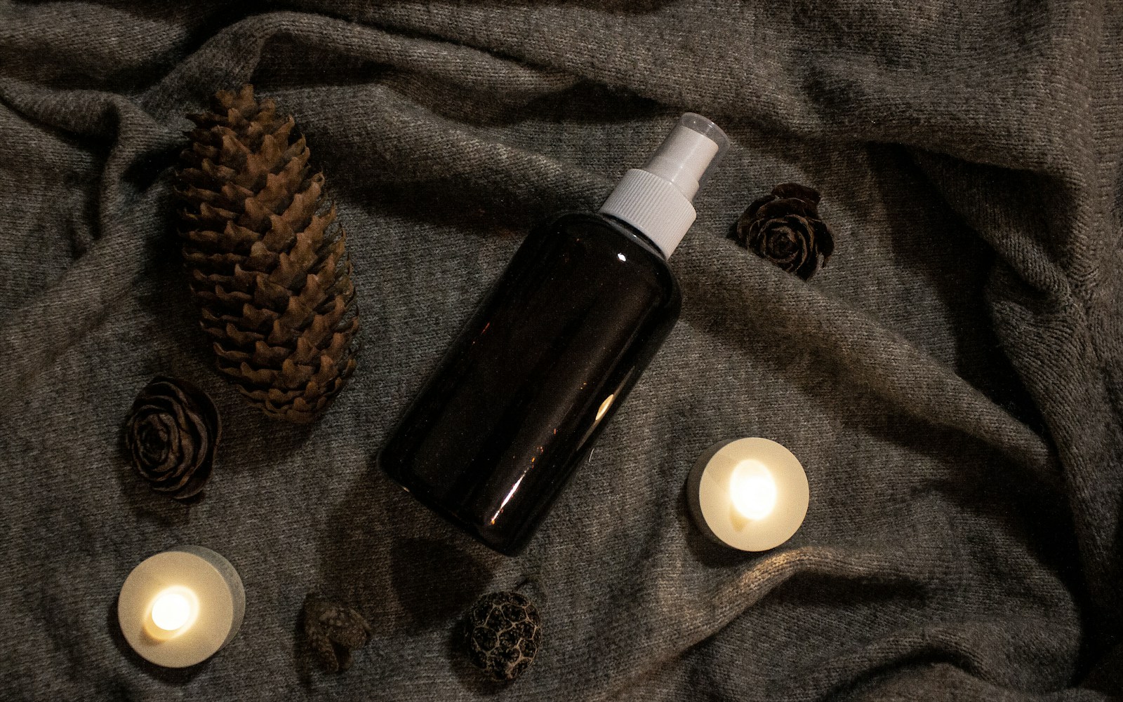 a bottle of lotion sitting on top of a bed next to candles